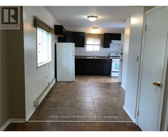 A kitchen with black cabinets and a white refrigerator.