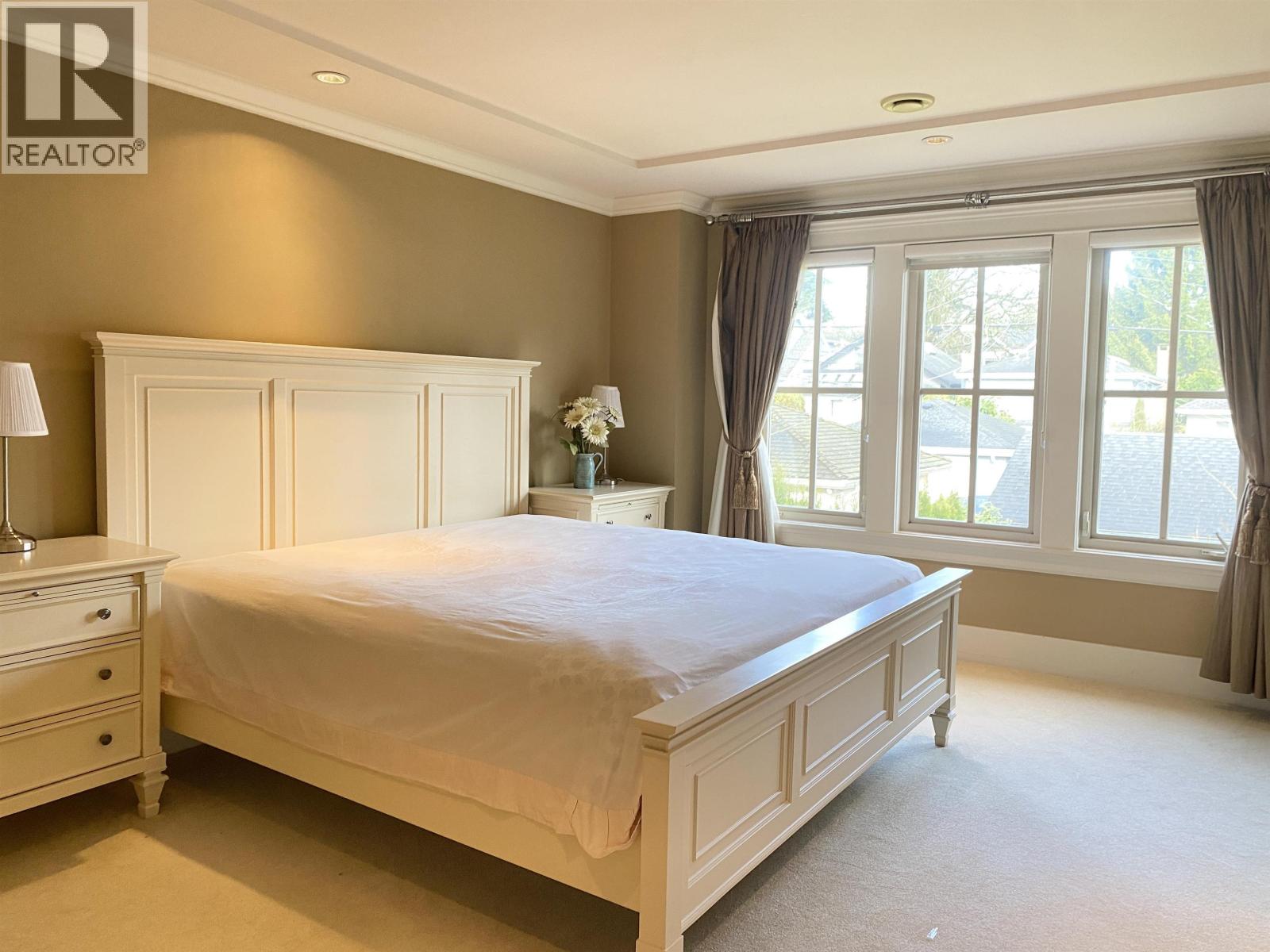 A bedroom with a bed, nightstand, and window.