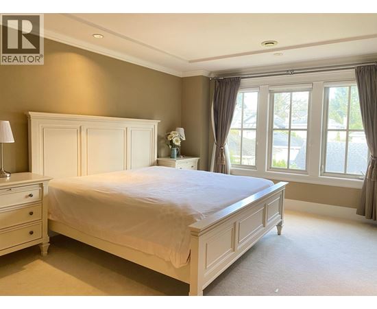 A bedroom with a bed, nightstand, and window.