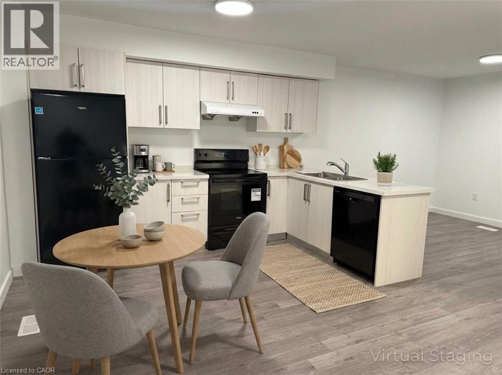 A modern kitchen with a black fridge, black oven, and a wooden table with two grey chairs.