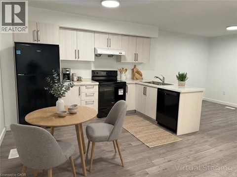 A modern kitchen with a black fridge, black oven, and a wooden table with two grey chairs.