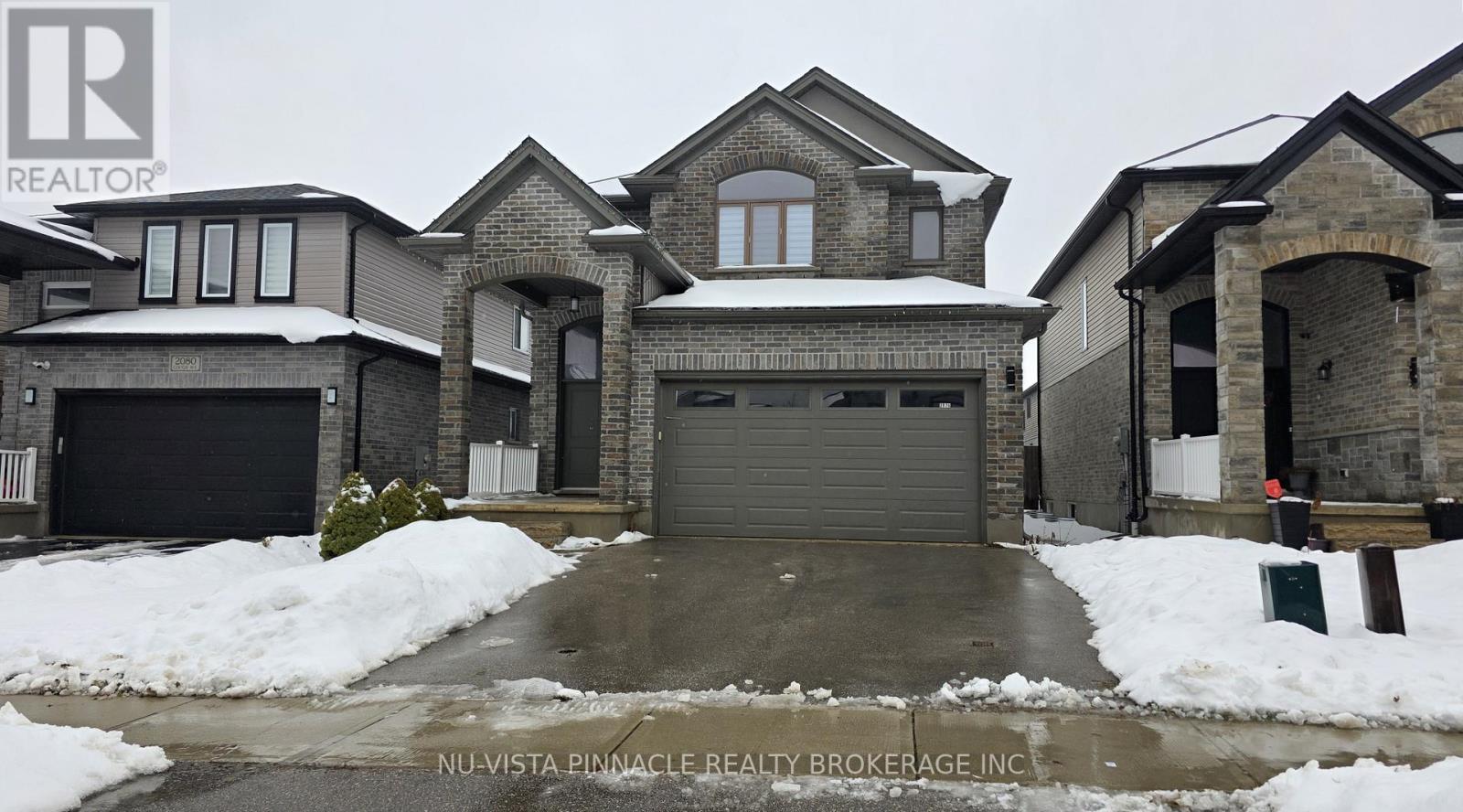 A large house with a snow-covered driveway in front.