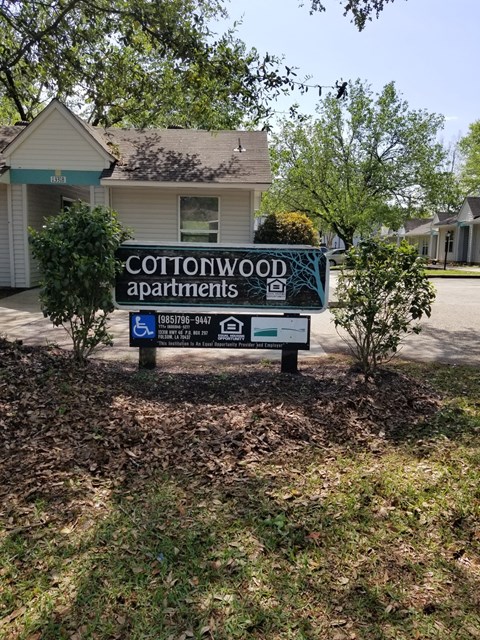 A sign for Cottonwood Apartments is in front of a building.