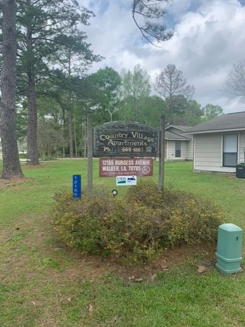 A sign in front of a house that says County Village Apartment.