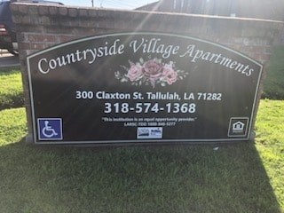 A sign for Countryside Village Apartments with a phone number and address.