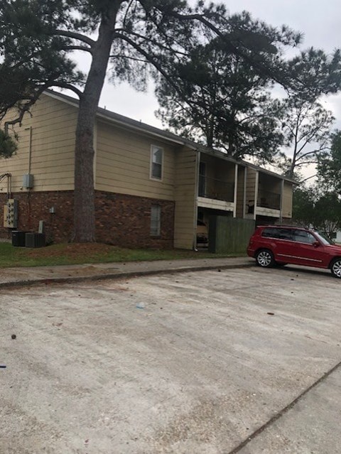 A red car is parked in front of a two-story apartment building.