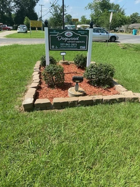 A sign for Dogwood Apartments is in the foreground with a parking lot in the background.