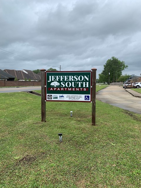 A sign for Jefferson South Apartments stands in a grassy area.