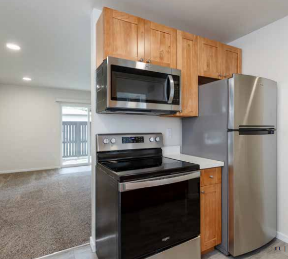 A kitchen with a stainless steel refrigerator and an oven with a microwave above it.