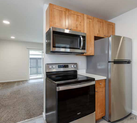 A kitchen with a stainless steel refrigerator and an oven with a microwave above it.