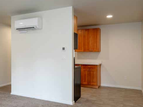 A black refrigerator is in a kitchen with wooden cabinets.