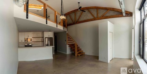 A spacious room with a staircase and a fireplace.
