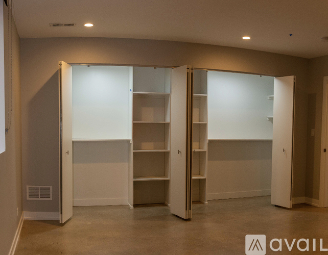Three white closet doors are open in a room.