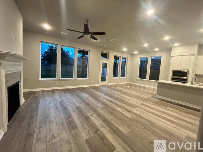 A spacious room with wooden flooring and a ceiling fan.