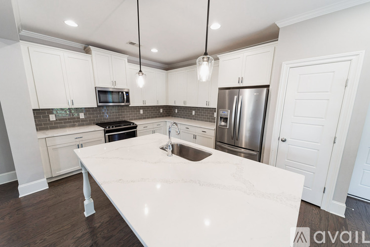 A kitchen with white cabinets and a marble countertop.