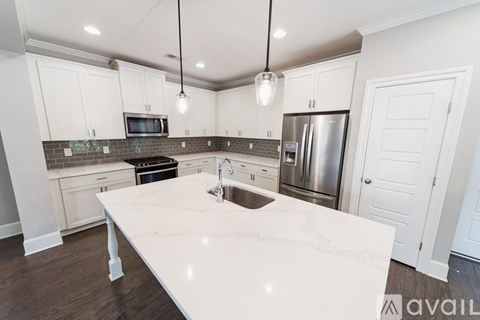 A kitchen with white cabinets and a marble countertop.