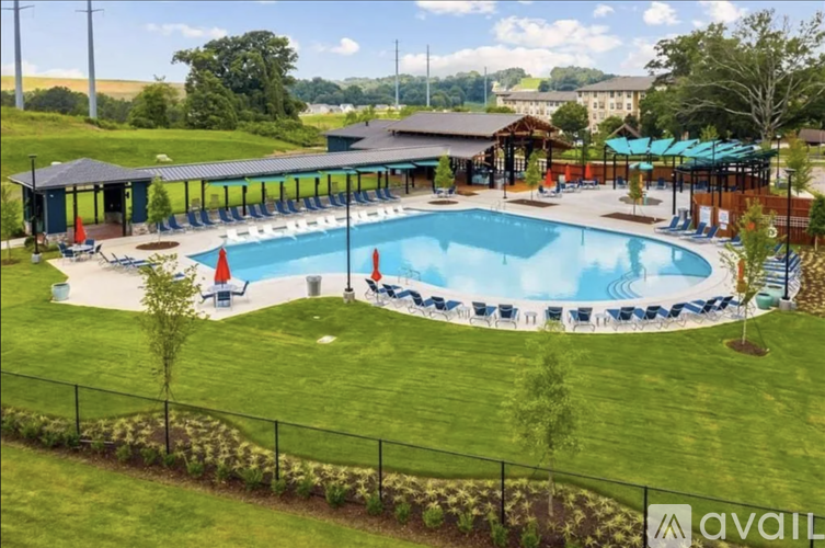 A large outdoor swimming pool surrounded by a grassy area and a pavilion.