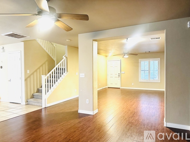 A spacious room with a staircase and a ceiling fan.