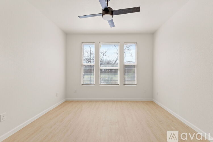 A room with a ceiling fan and a window with a view of trees outside.