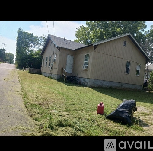 A house with a red container and a black bag in front of it.