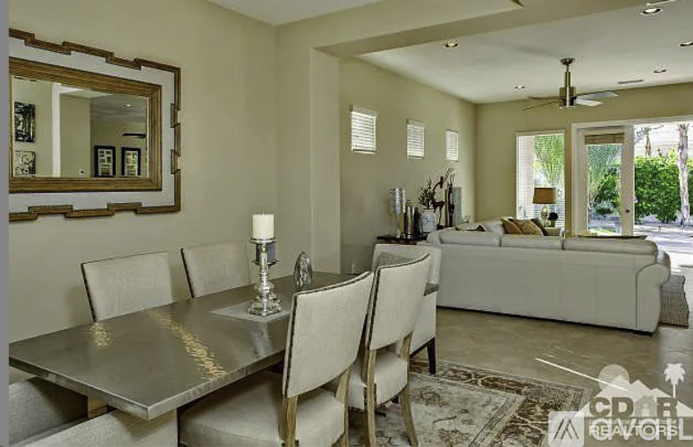 A modern dining room with a glass table and white chairs.