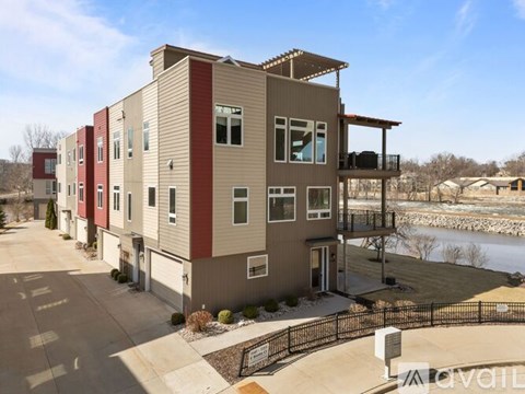 A modern apartment building with a balcony overlooking a body of water.