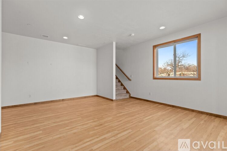 A room with wooden floors and a window showing a tree outside.