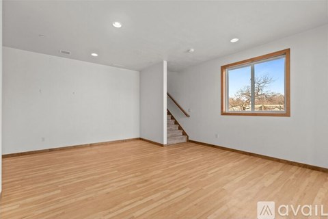 A room with wooden floors and a window showing a tree outside.