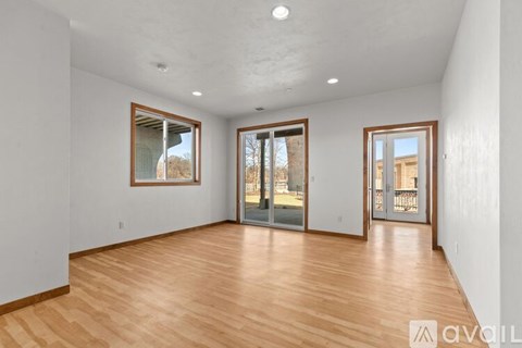 A spacious room with wooden floors and three sliding glass doors.