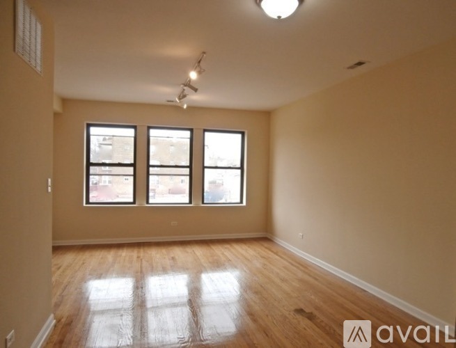 A room with wooden floors and three windows.