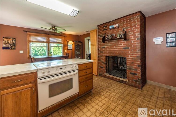 A kitchen with a white stove top oven and a brick fireplace.