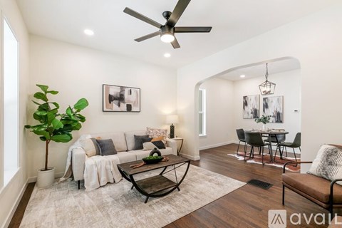 A living room with a white couch, a coffee table, and a dining table set up in the background.