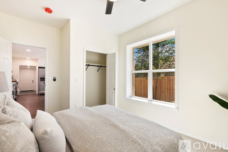 A bedroom with a large bed and a window overlooking a wooden fence.