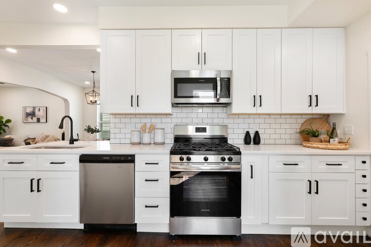 A kitchen with white cabinets and a black stove top oven.