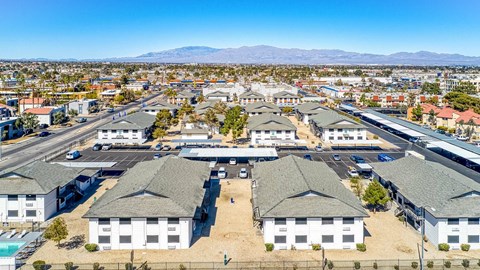 A large white building complex with a parking lot in front and mountains in the background.