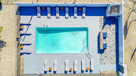 A rectangular pool with a blue tiled edge and sun loungers on the side.
