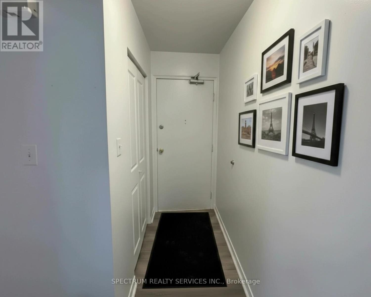 A hallway with a black carpet and pictures on the wall.