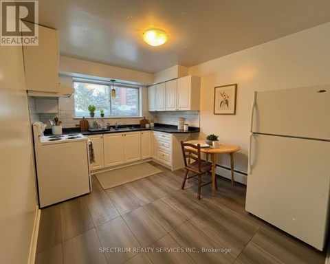 A kitchen with white appliances and wooden floors.