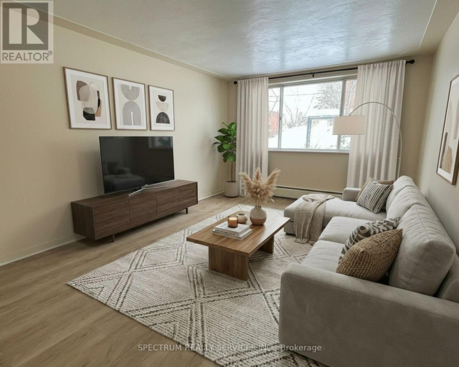 A living room with a grey couch, a wooden coffee table, and a flat screen TV on a cabinet.
