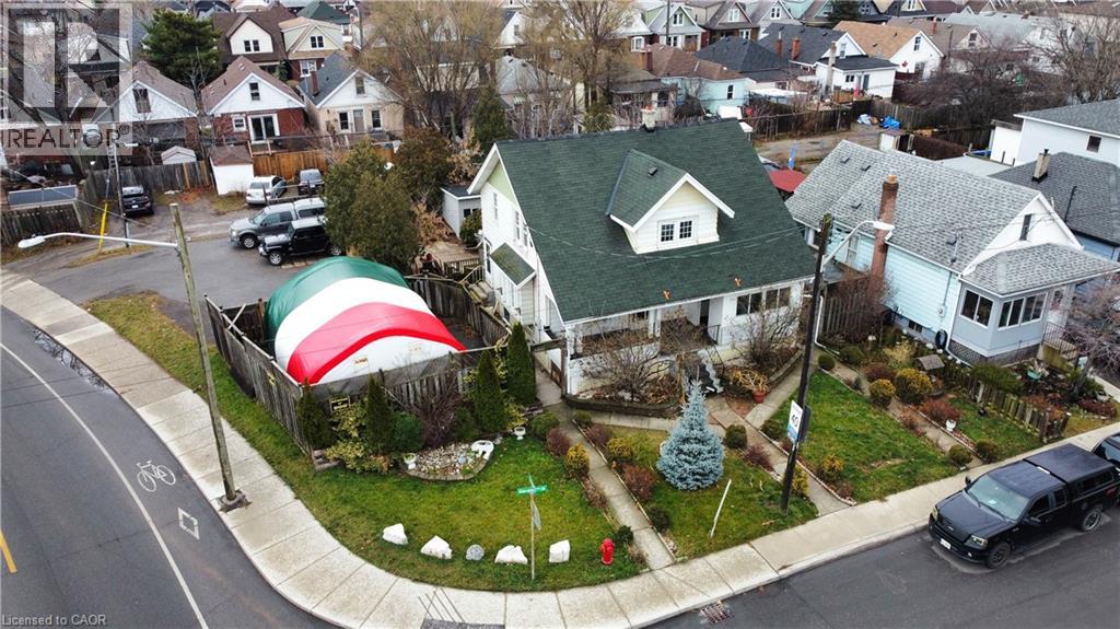 A house with a green roof is surrounded by a fence and a Christmas tree.