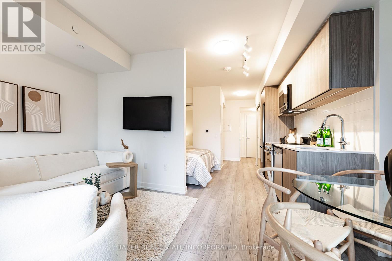 A modern living room with a white couch and a television on the wall.