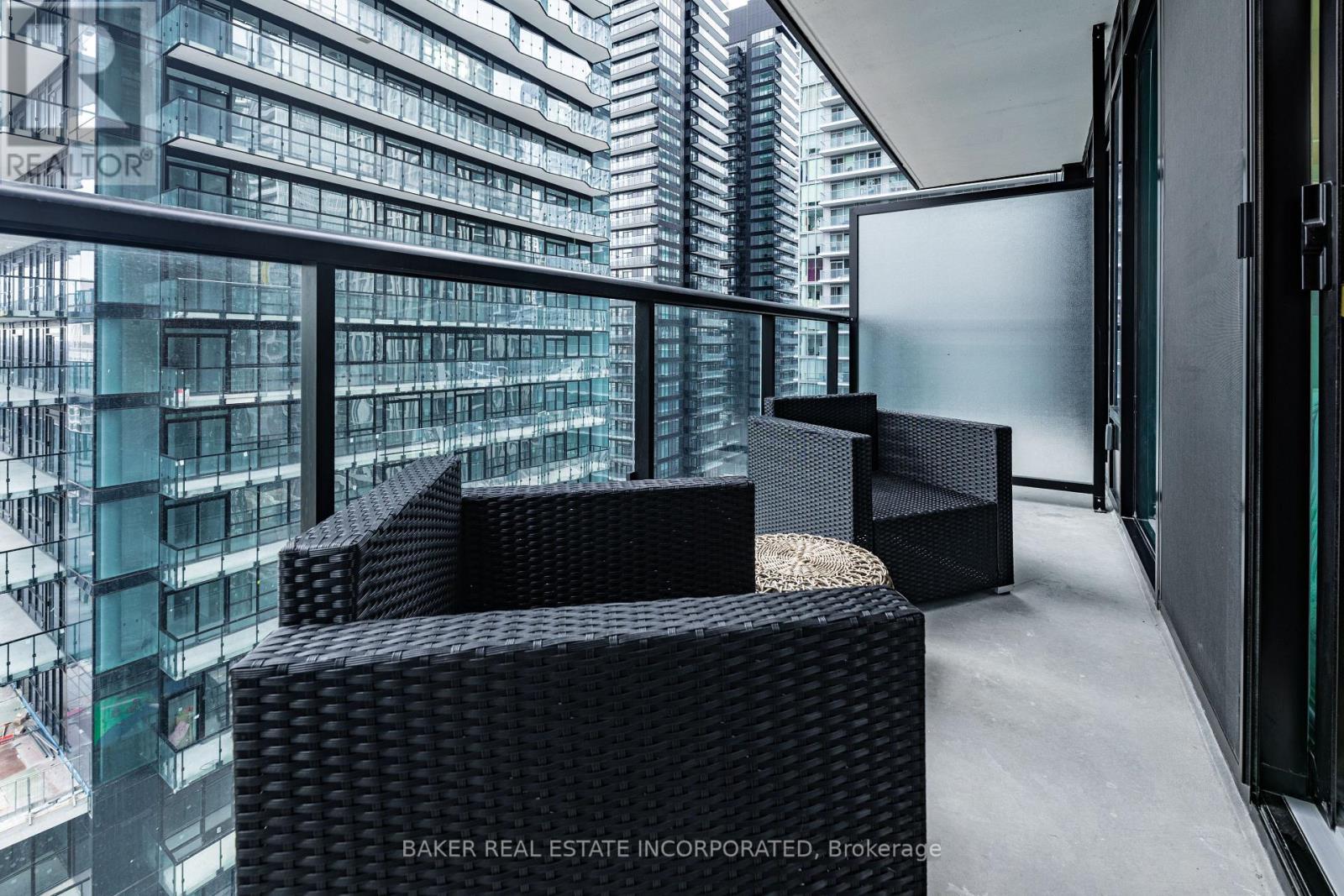 A modern interior space with black furniture and a glass wall overlooking a cityscape.