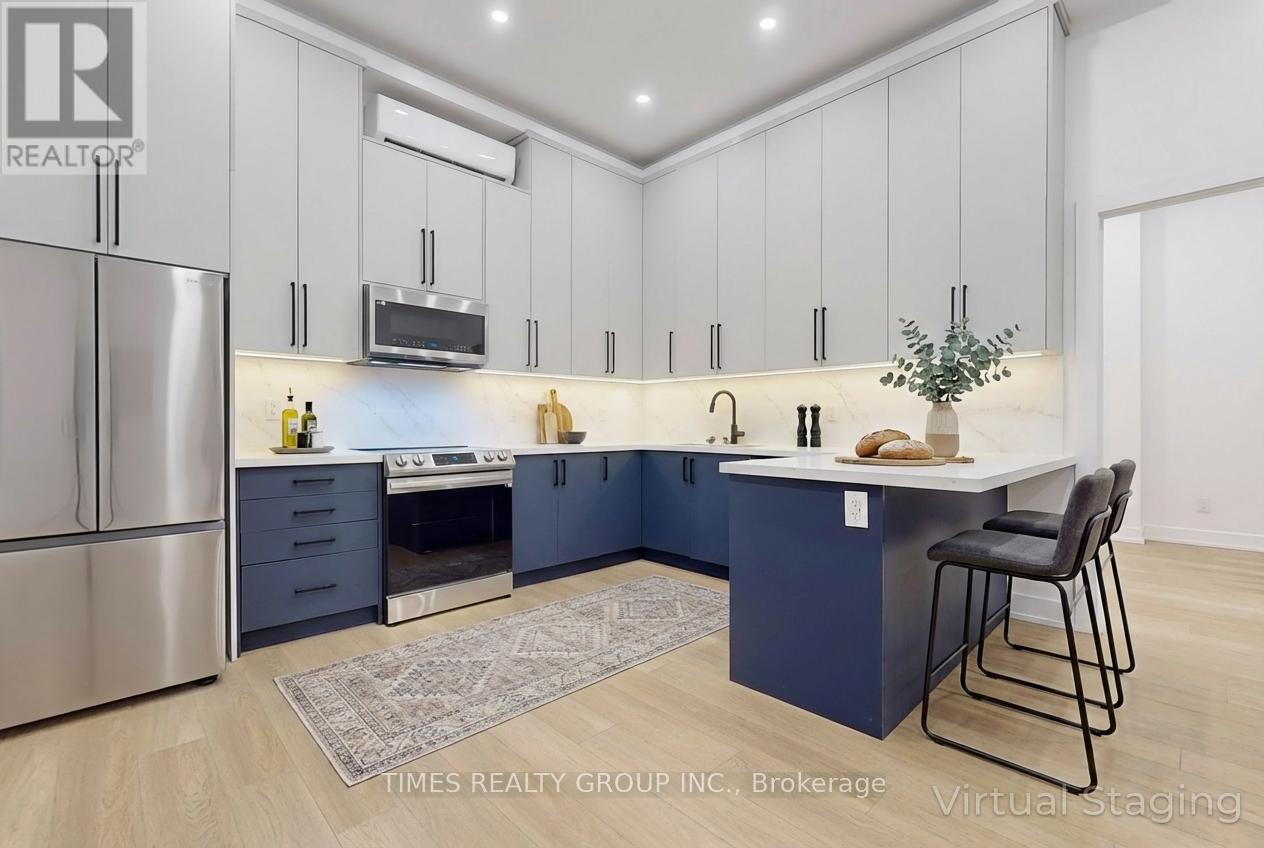 A modern kitchen with a stainless steel refrigerator and a central island with a countertop and bar stools.