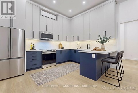 A modern kitchen with a stainless steel refrigerator and a central island with a countertop and bar stools.