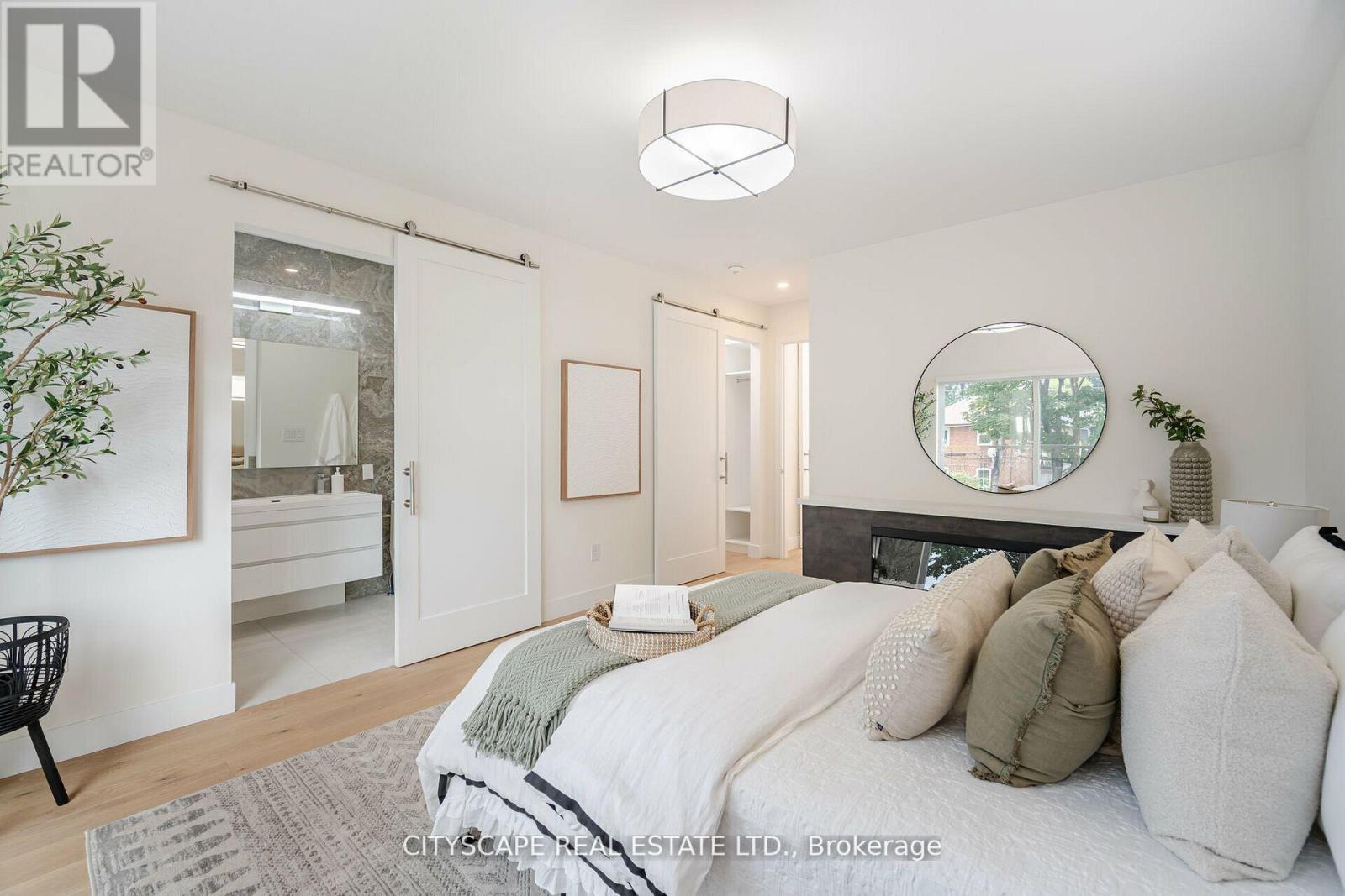 A bedroom with a bed, a chair, and a mirror on the wall.