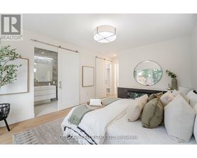A bedroom with a bed, a chair, and a mirror on the wall.