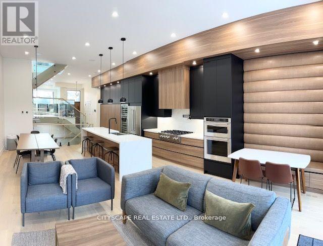 A modern living room with a grey sofa and a kitchen area in the background.