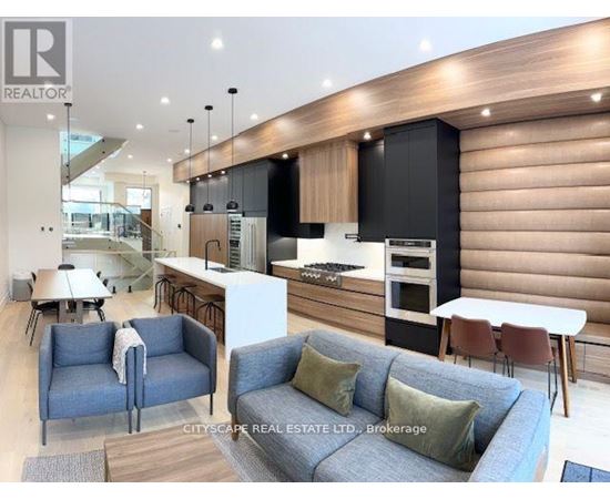 A modern living room with a grey sofa and a kitchen area in the background.