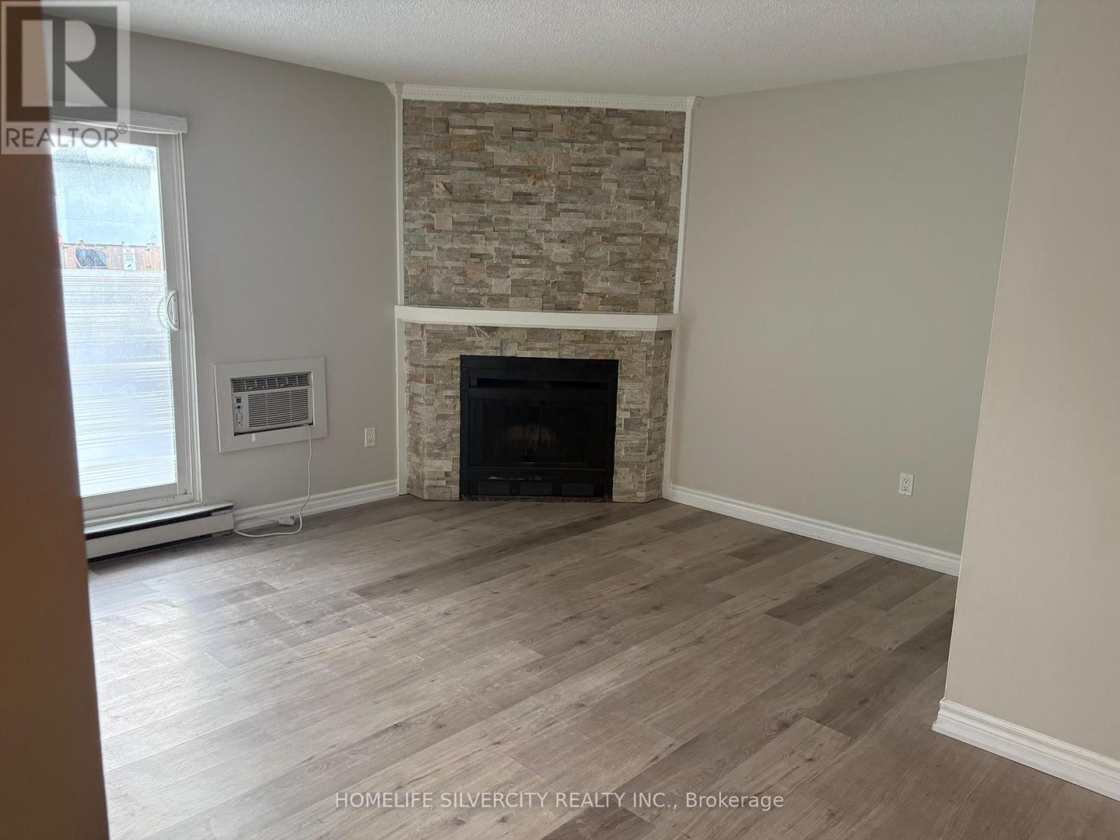 A living room with a stone fireplace and wood flooring.