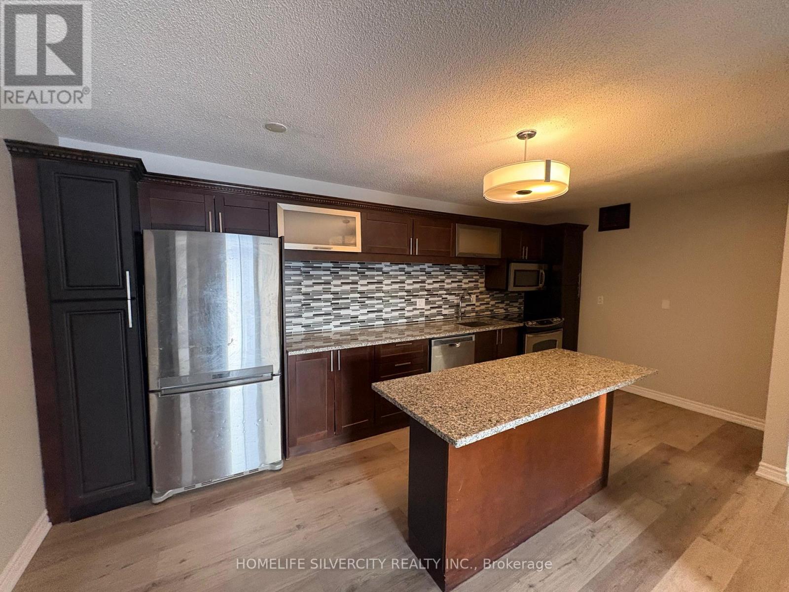 A kitchen area with a refrigerator, microwave, and a countertop.